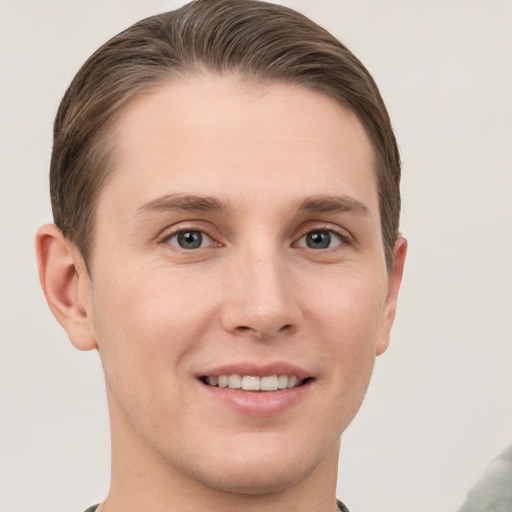 Joyful white young-adult male with short  brown hair and grey eyes