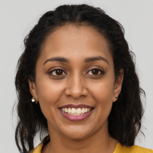 Joyful black young-adult female with long  brown hair and brown eyes