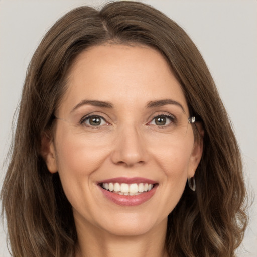 Joyful white adult female with long  brown hair and grey eyes