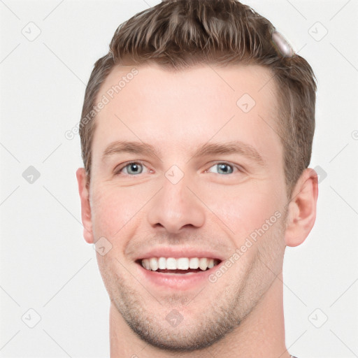 Joyful white young-adult male with short  brown hair and grey eyes