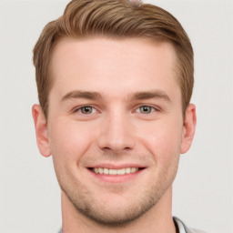 Joyful white young-adult male with short  brown hair and grey eyes