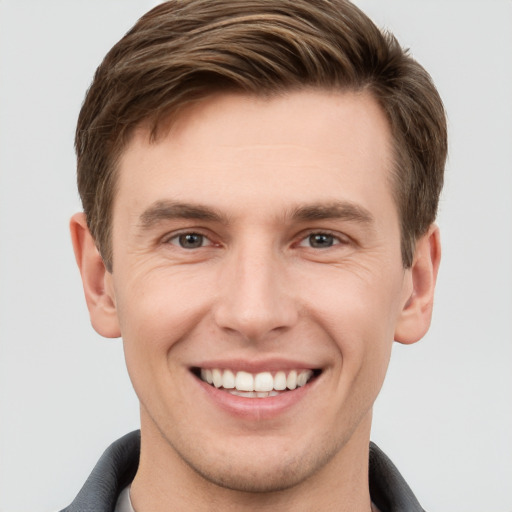 Joyful white young-adult male with short  brown hair and grey eyes