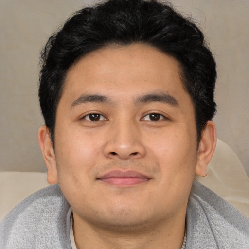 Joyful asian young-adult male with short  black hair and brown eyes