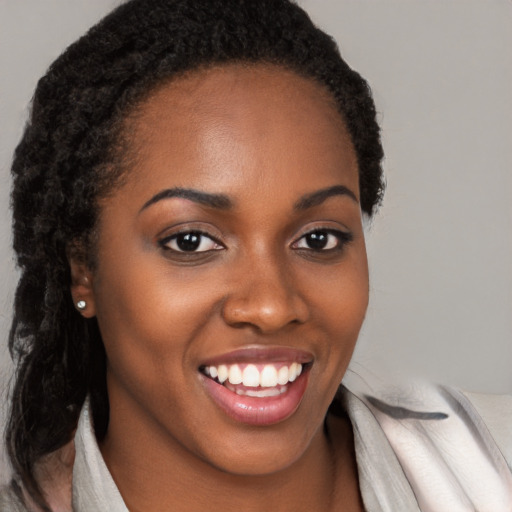 Joyful black young-adult female with long  brown hair and brown eyes