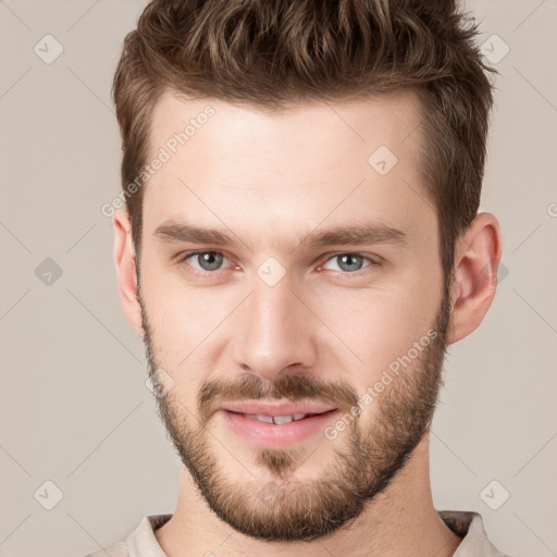 Joyful white young-adult male with short  brown hair and grey eyes