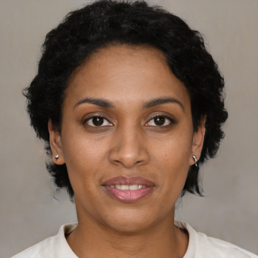 Joyful black young-adult female with short  black hair and brown eyes