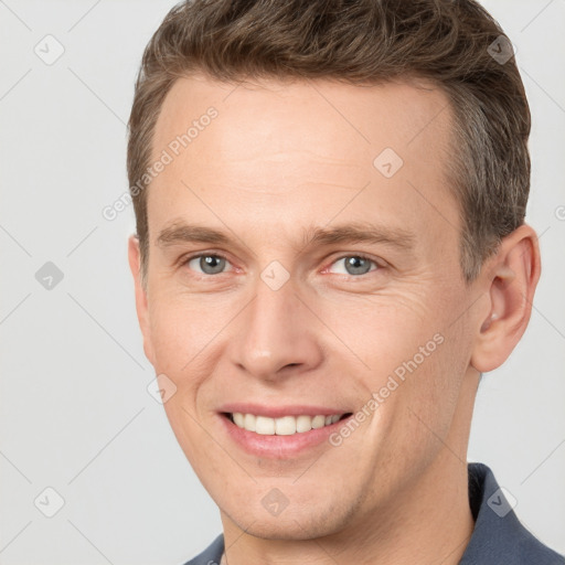 Joyful white young-adult male with short  brown hair and grey eyes