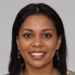 Joyful black young-adult female with long  brown hair and brown eyes