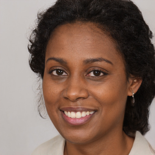Joyful black adult female with long  brown hair and brown eyes