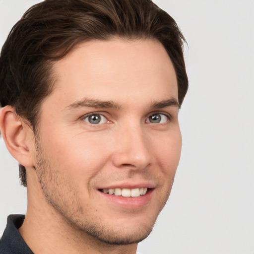 Joyful white young-adult male with short  brown hair and grey eyes