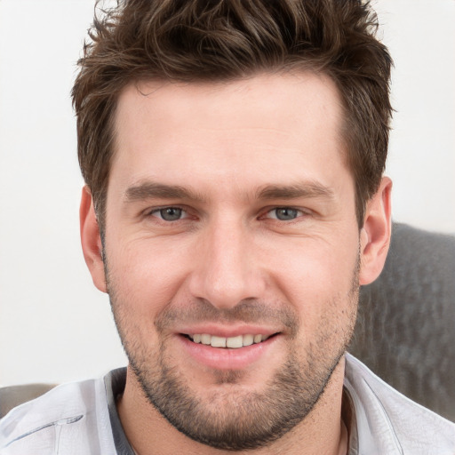 Joyful white young-adult male with short  brown hair and grey eyes