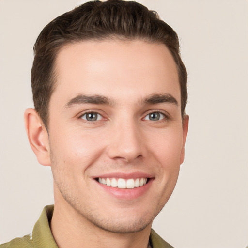 Joyful white young-adult male with short  brown hair and grey eyes