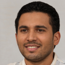 Joyful latino young-adult male with short  black hair and brown eyes