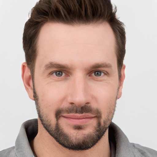 Joyful white young-adult male with short  brown hair and grey eyes