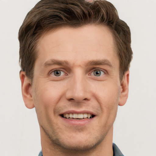 Joyful white young-adult male with short  brown hair and grey eyes