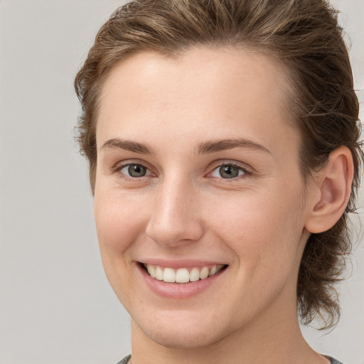 Joyful white young-adult female with medium  brown hair and grey eyes