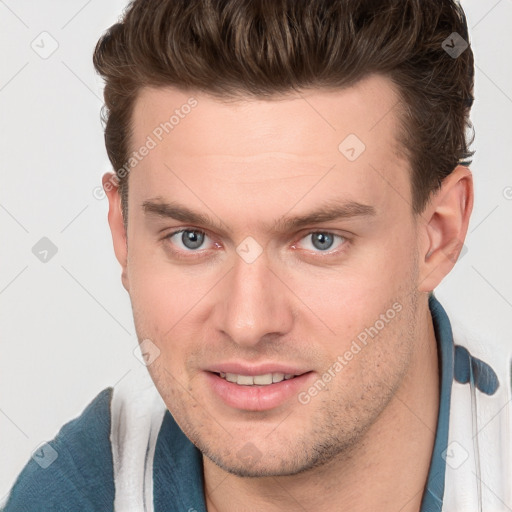 Joyful white young-adult male with short  brown hair and grey eyes