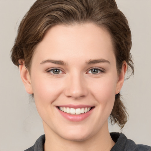 Joyful white young-adult female with medium  brown hair and grey eyes