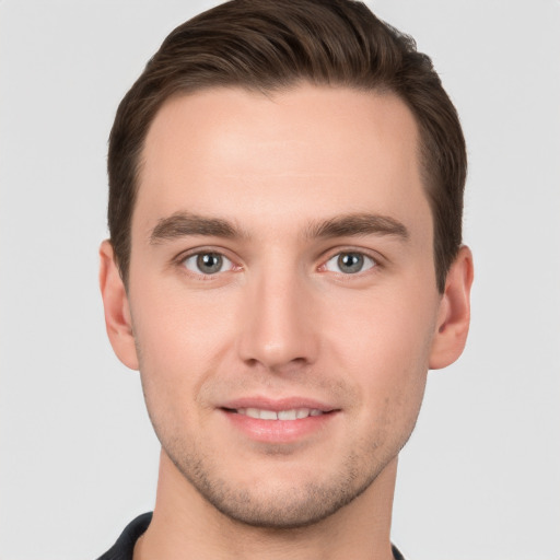 Joyful white young-adult male with short  brown hair and grey eyes