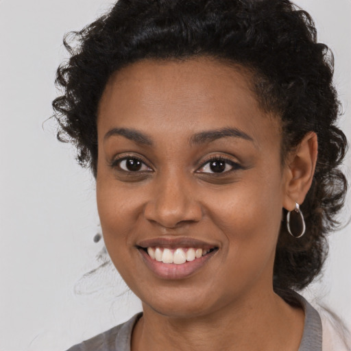 Joyful black young-adult female with long  brown hair and brown eyes