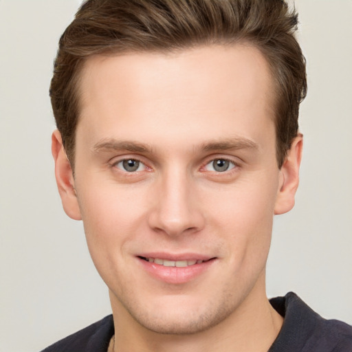 Joyful white young-adult male with short  brown hair and grey eyes