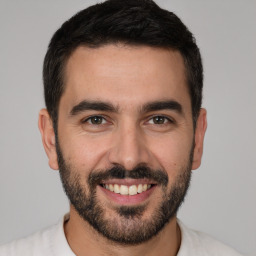 Joyful white young-adult male with short  black hair and brown eyes