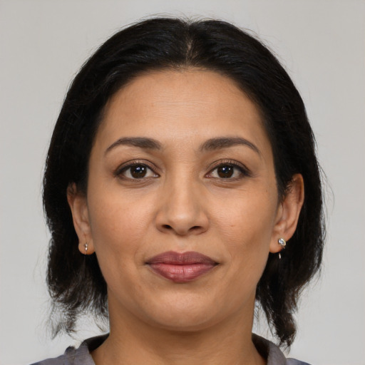 Joyful latino adult female with medium  brown hair and brown eyes