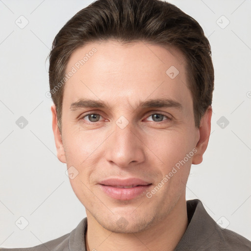 Joyful white young-adult male with short  brown hair and grey eyes