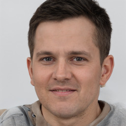 Joyful white young-adult male with short  brown hair and grey eyes