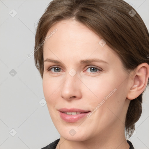 Joyful white young-adult female with medium  brown hair and grey eyes