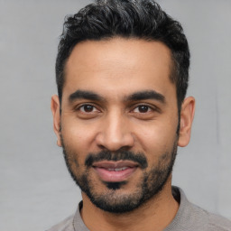 Joyful latino young-adult male with short  black hair and brown eyes