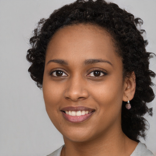 Joyful black young-adult female with long  black hair and brown eyes