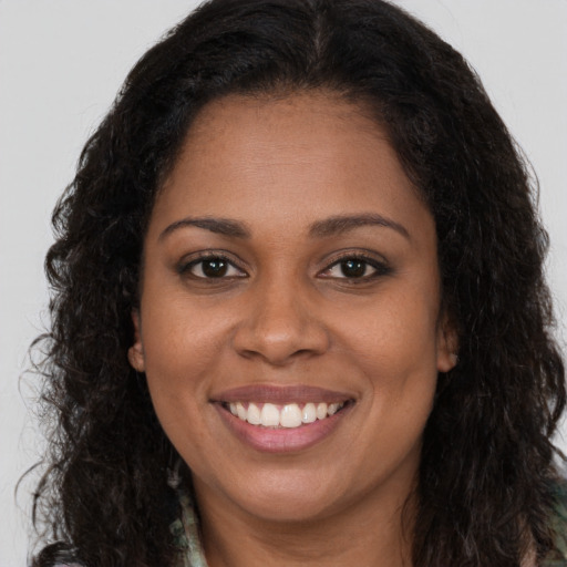Joyful black young-adult female with long  brown hair and brown eyes