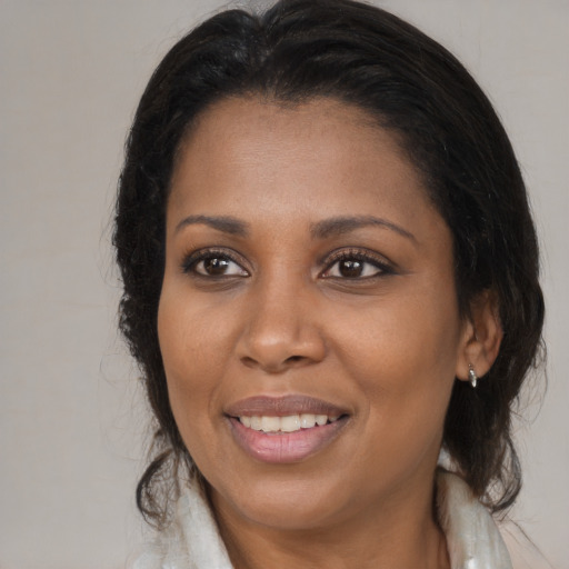 Joyful black young-adult female with long  brown hair and brown eyes