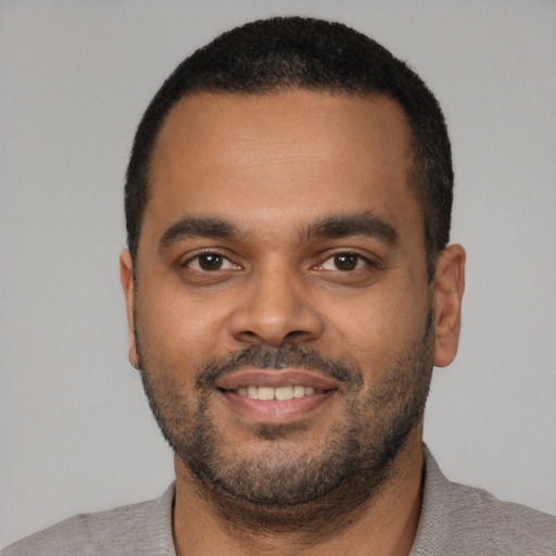 Joyful black young-adult male with short  black hair and brown eyes
