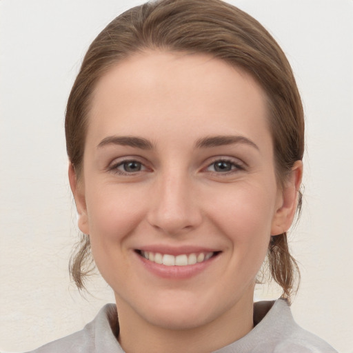 Joyful white young-adult female with medium  brown hair and grey eyes