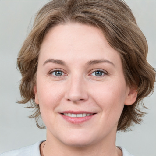 Joyful white young-adult female with medium  brown hair and grey eyes