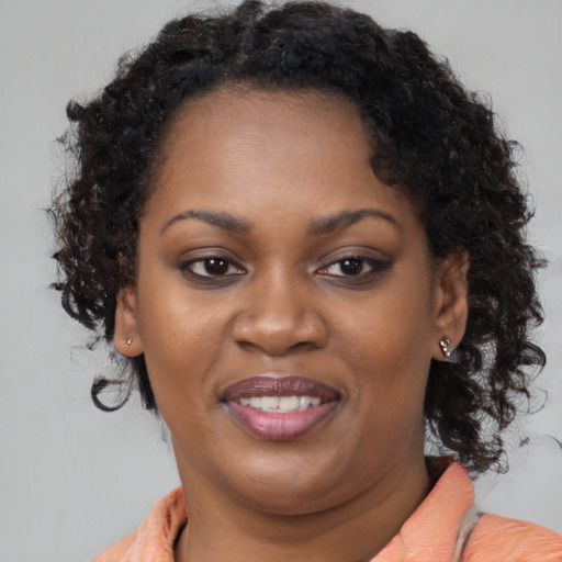 Joyful black young-adult female with long  brown hair and brown eyes
