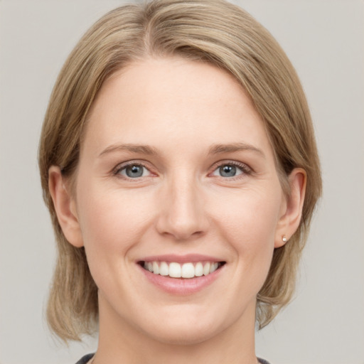 Joyful white young-adult female with medium  brown hair and grey eyes