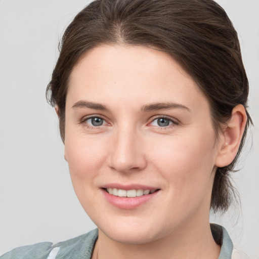 Joyful white young-adult female with medium  brown hair and grey eyes