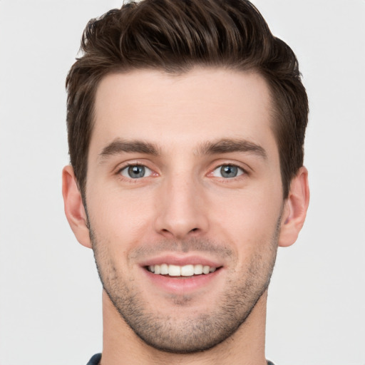 Joyful white young-adult male with short  brown hair and grey eyes