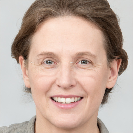 Joyful white adult female with medium  brown hair and grey eyes