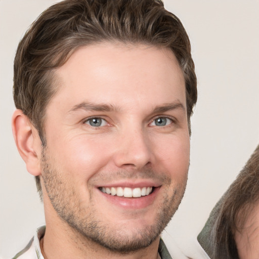 Joyful white young-adult male with short  brown hair and grey eyes