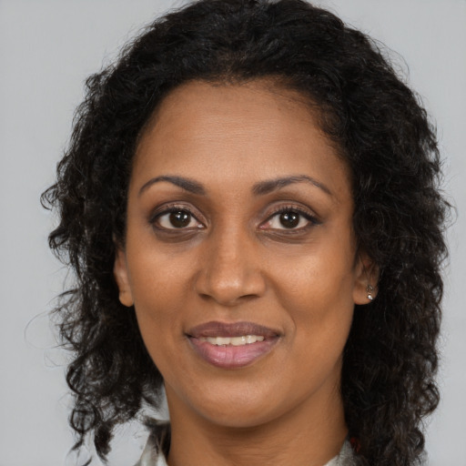 Joyful black adult female with long  brown hair and brown eyes