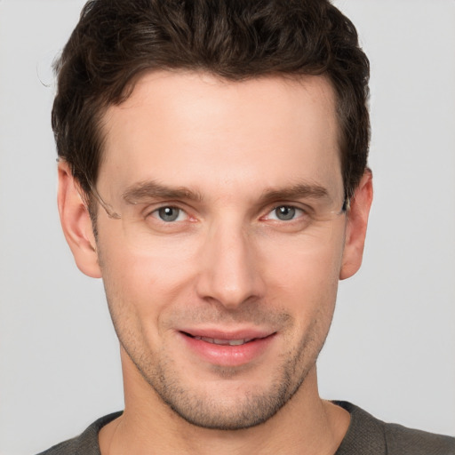 Joyful white young-adult male with short  brown hair and grey eyes