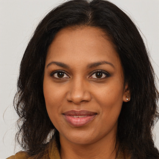 Joyful black young-adult female with long  brown hair and brown eyes