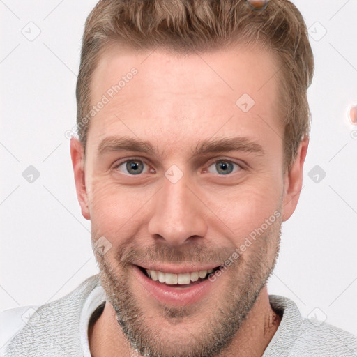 Joyful white young-adult male with short  brown hair and blue eyes