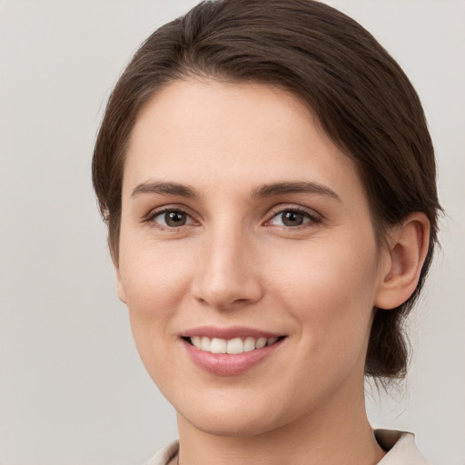 Joyful white young-adult female with medium  brown hair and grey eyes