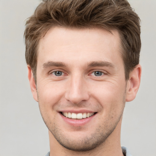 Joyful white young-adult male with short  brown hair and grey eyes