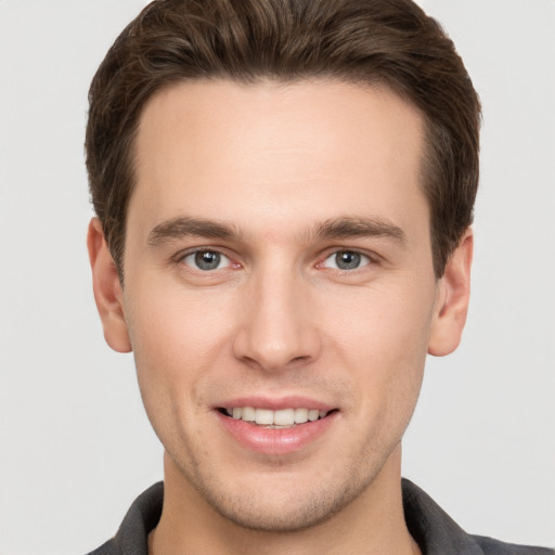 Joyful white young-adult male with short  brown hair and grey eyes